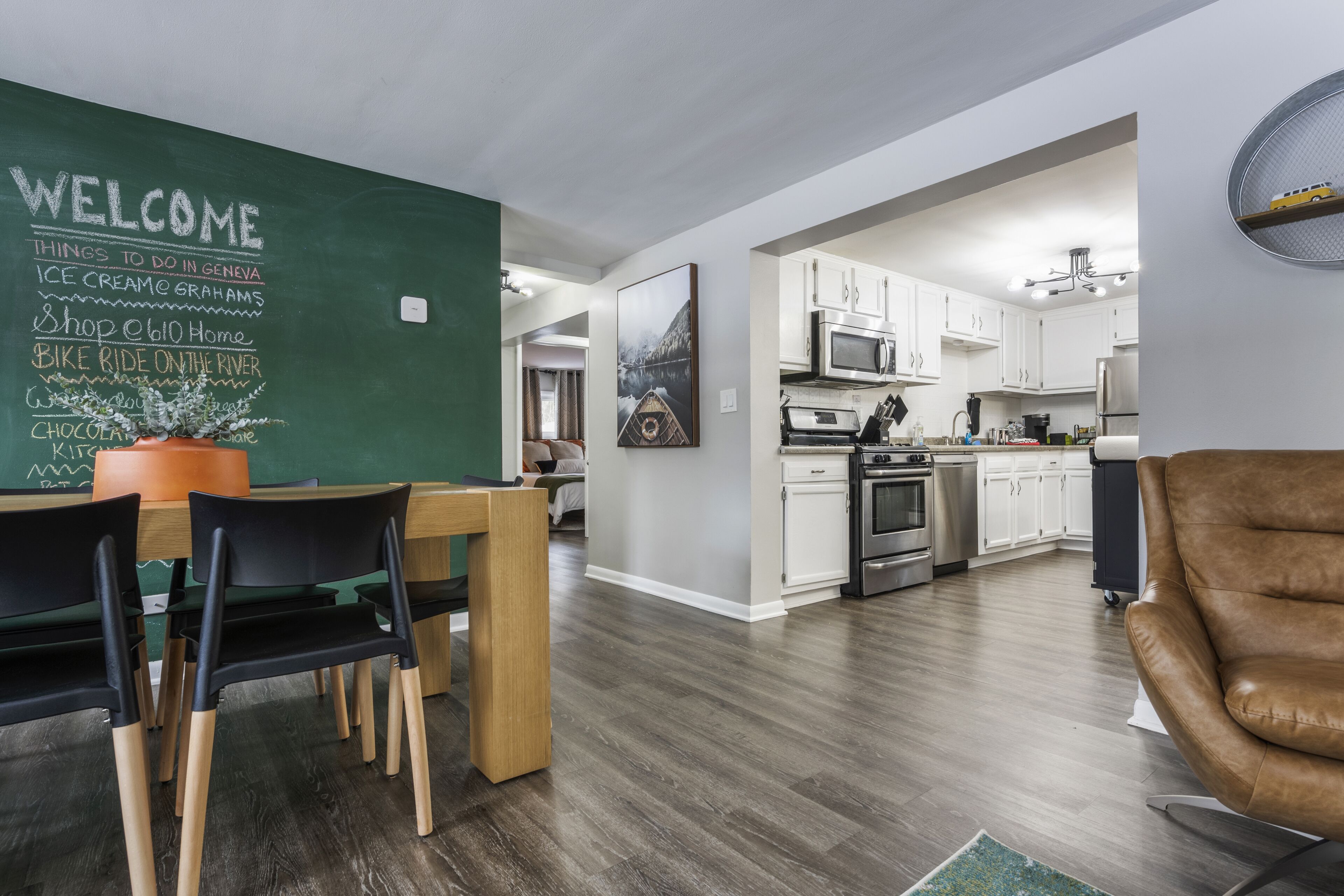 A modern kitchen with white cabinets, stainless steel appliances, and a dining area with a wooden table and chairs.