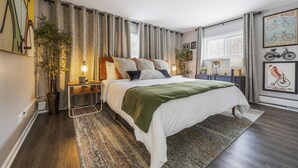 Una camera da letto moderna con un letto grande, tende a motivi decorativi e un quadro a tema bicicletta.