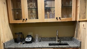 Une cuisine avec des meubles en bois, un plan de travail en granit et un évier en acier inoxydable.