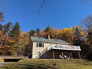 A two-story house with a balcony, surrounded by trees with autumn foliage.