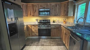 Une cuisine dotée de meubles en bois, d’un réfrigérateur en acier inoxydable, d’un four à micro-ondes et d’une cuisinière.