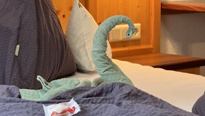 Una cama con un edredón gris oscuro, una toalla verde y una almohada.