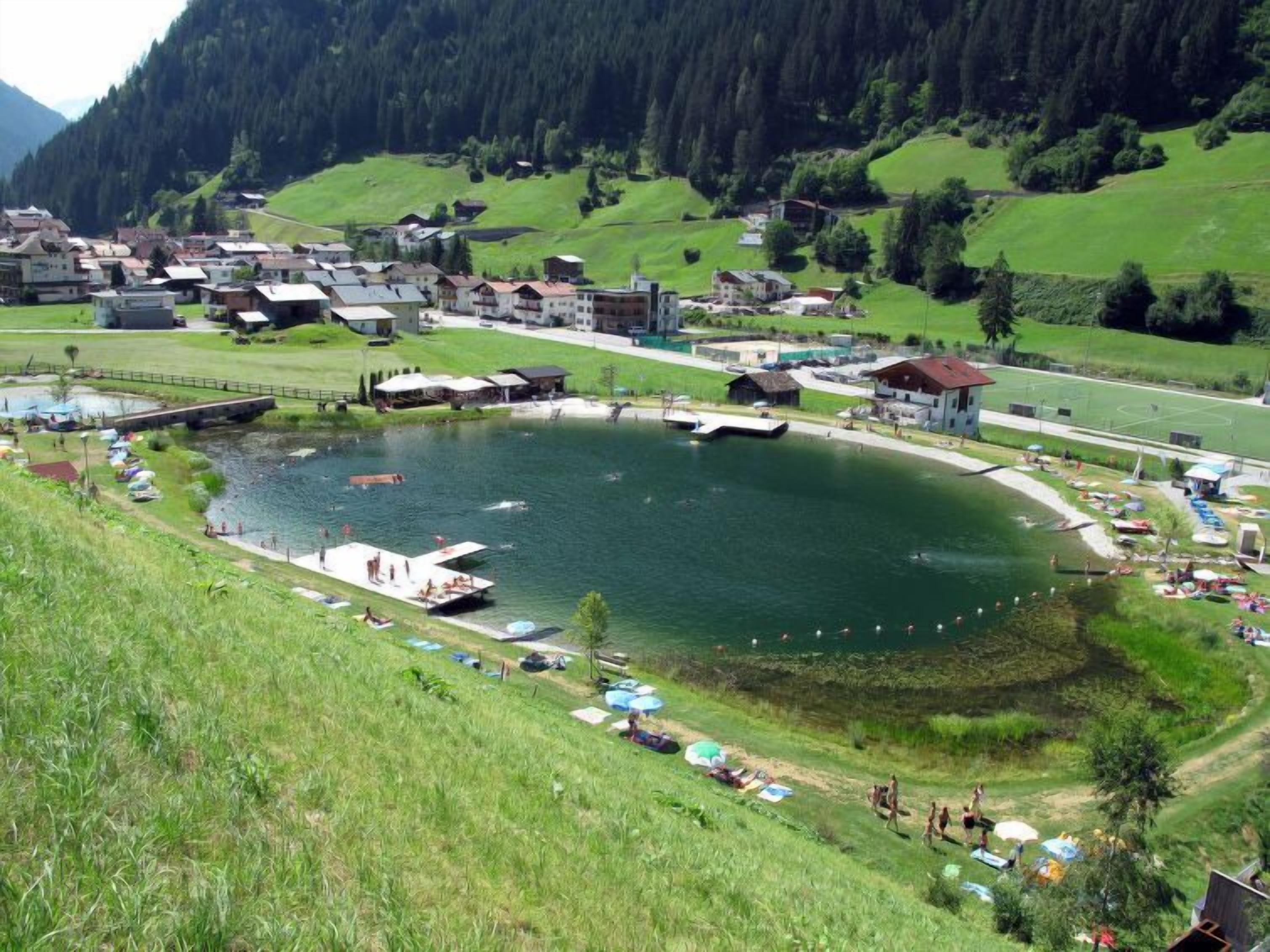 A lakeside village with a central pond, surrounded by houses and a small dock.