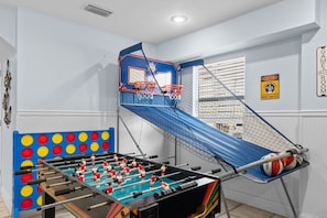 Um quarto com mesa de pebolim, cesta de basquete e quadra de basquete.