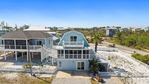 Une maison située sur la côte, dotée d’un balcon, d’une véranda et d’une plage de sable.