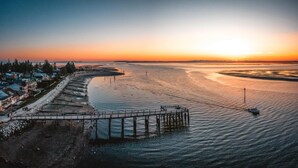 Une zone côtière avec une jetée qui s’avance dans l’eau, entourée de bâtiments résidentiels.