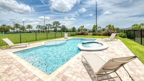 A rectangular swimming pool with a hot tub, surrounded by a brick patio and two lounge chairs. - Trendy 5BR Villa with Private Pool Near Disney (Kissimmee)