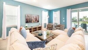A living room with a beige sofa, two armchairs, a coffee table, and a painting on the wall. - Trendy 5BR Villa with Private Pool Near Disney (Kissimmee)