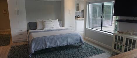 A bedroom with a bed, wardrobe, TV, and a window.