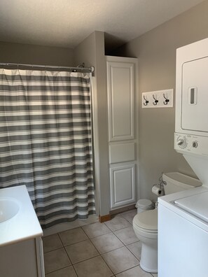 Bathroom features a striped shower curtain, white toilet, and sink, along with a cabinet and mirror above.