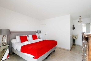 A hotel room with a large bed, two bedside tables with lamps, a dresser, a mirror, and a chandelier. - Appartement Standing, 90m² Climatisé à 5 mns à Pied de la Croisette et Plages (Cannes)