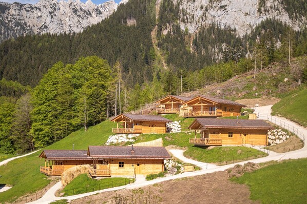 Un grupo de cabañas de madera con balcones, ubicadas en una ladera con vista a una montaña.