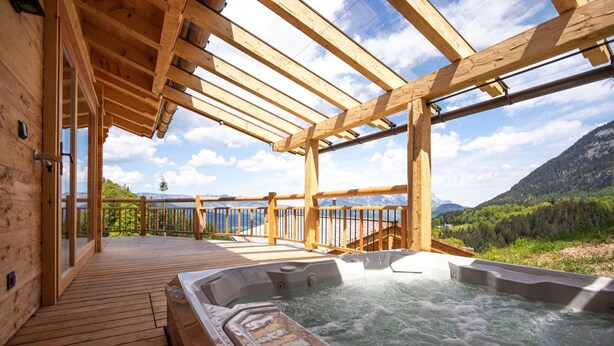 Une terrasse en bois avec un jacuzzi et une vue sur les montagnes.
