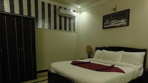 A bedroom with a bed, a wardrobe, a patterned rug, and a framed picture on the wall. - Triple One Hotel Suites (Abbottabad)