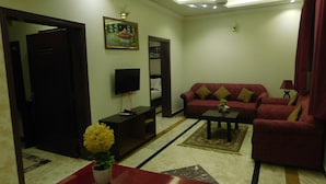 A living room with a sofa, a TV, a coffee table, and a plant. - Triple One Hotel Suites (Abbottabad)