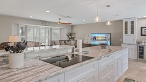 A spacious kitchen with a large island, white cabinetry, and pendant lighting. - Prestigious location, Gulf Access, Heated Pool - Villa Pineapple Oasis - Roelens Vacations (Cape Coral)