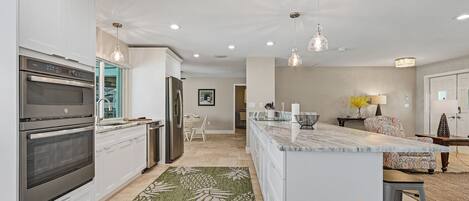 A modern kitchen with white cabinetry, stainless steel appliances, and a central island.