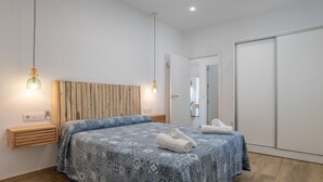 A modern bedroom with a patterned bedspread, bedside lamps, a wooden headboard, and a wardrobe. - Holiday Home "Casa Trafalmar" with Pool, Wi-Fi, Garden and Terrace (Zahora)