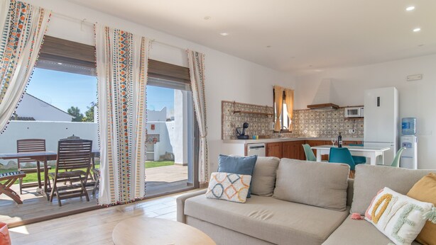 A living room with a sofa, a table, and a view through a glass door to an outdoor patio. - Holiday Home "Casa Trafalmar" with Pool, Wi-Fi, Garden and Terrace (Zahora)