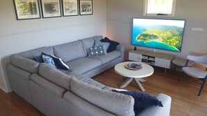Una sala de estar con un sofá gris, una mesa de centro, un televisor y cuadros en la pared.