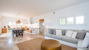 A spacious living area with a sofa, a dining table, and a kitchen in the background. - Villa "Fora" near the Sea with Pool, Wi-Fi, Garden & Terrace (Carovigno)