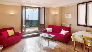A room with a red sofa, a small table, a chair, and a view through a door to an outdoor balcony. - Apartment "Helvetia" on Lake Como with Lake View, Wi-Fi & Terrace (Tremezzina)