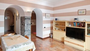 A living room with a television, wooden shelves, and a dining area with a table and chairs. - Apartment "Helvetia" on Lake Como with Lake View, Wi-Fi & Terrace (Tremezzina)