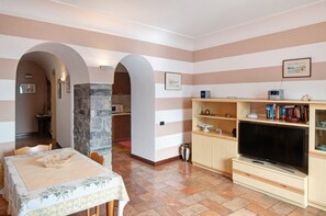 Una sala de estar con televisor, estanterías de madera y un comedor con mesa y sillas.
