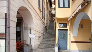 A narrow street with a staircase leading to a building with a blue door and a signboard. - Apartment "Helvetia" on Lake Como with Lake View, Wi-Fi & Terrace (Tremezzina)