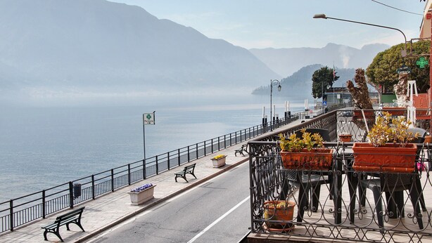 A coastal promenade with a bench, potted plants, and a view of the sea and mountains. - Apartment "Helvetia" on Lake Como with Lake View, Wi-Fi & Terrace (Tremezzina)