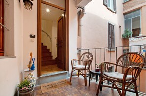 A balcony with wicker chairs, a small table, a decorative vase, and a door leading to an interior space. - Apartment "Ivana" close to the Lake with Wi-Fi & Balcony (Menaggio)