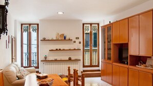 Un salón con una mesa de comedor de madera, un sofá y un mueble para la televisión.