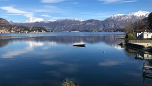 Un lago tranquilo con un bote, montañas al fondo y un edificio a la derecha.