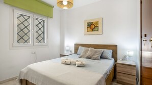 A bedroom with a bed, bedside tables, a nightstand, a lamp, a painting, and a window with a lattice design.