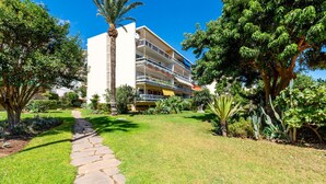 A multi-story building with balconies, surrounded by well-maintained lawns and various trees. - Apartment 'Eurosol Carihuela' with Shared Garden, Wi-Fi and Air Conditioning (Torremolinos)