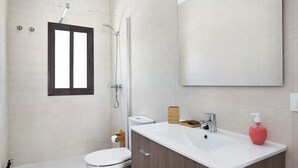 Een moderne badkamer met toilet, wastafel, spiegel, douche en een handdoekhouder.
