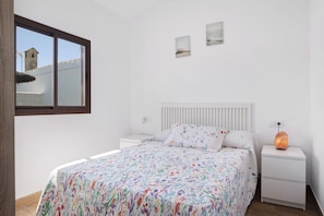 Une chambre à coucher comprenant un lit, une table de chevet, une fenêtre et un radiateur fixé au mur.
