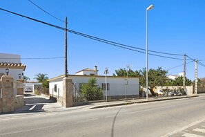 Une vue de rue avec un bâtiment blanc, une voiture garée et un ciel bleu dégagé.