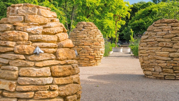 A pathway lined with stone structures, leading to a central area with a metal sculpture. - TWO BEDROOM LUXURY GROUND FLOOR APARTMENT.  (London)