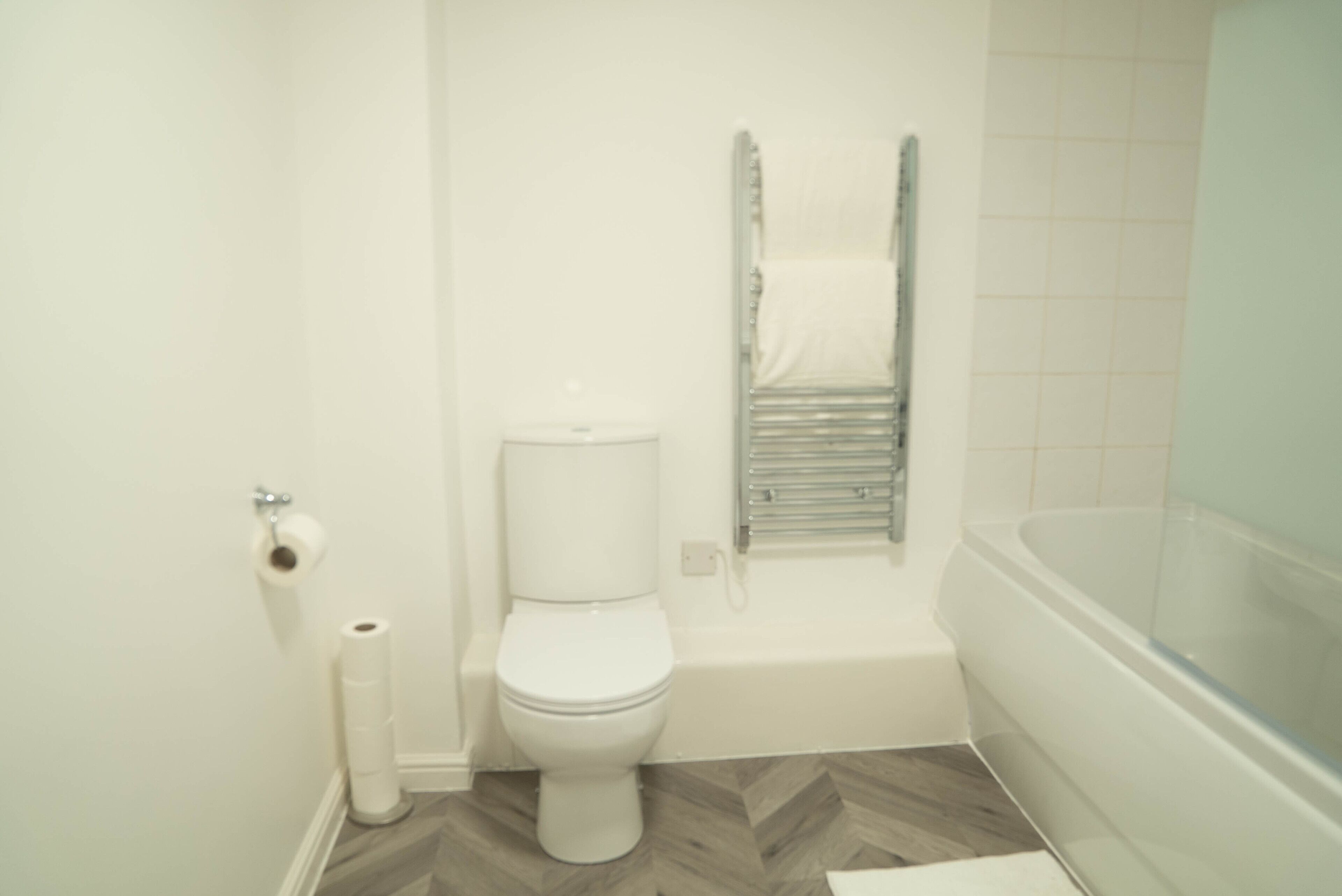 Un baño con inodoro, rollo de papel higiénico, ducha y bañera.