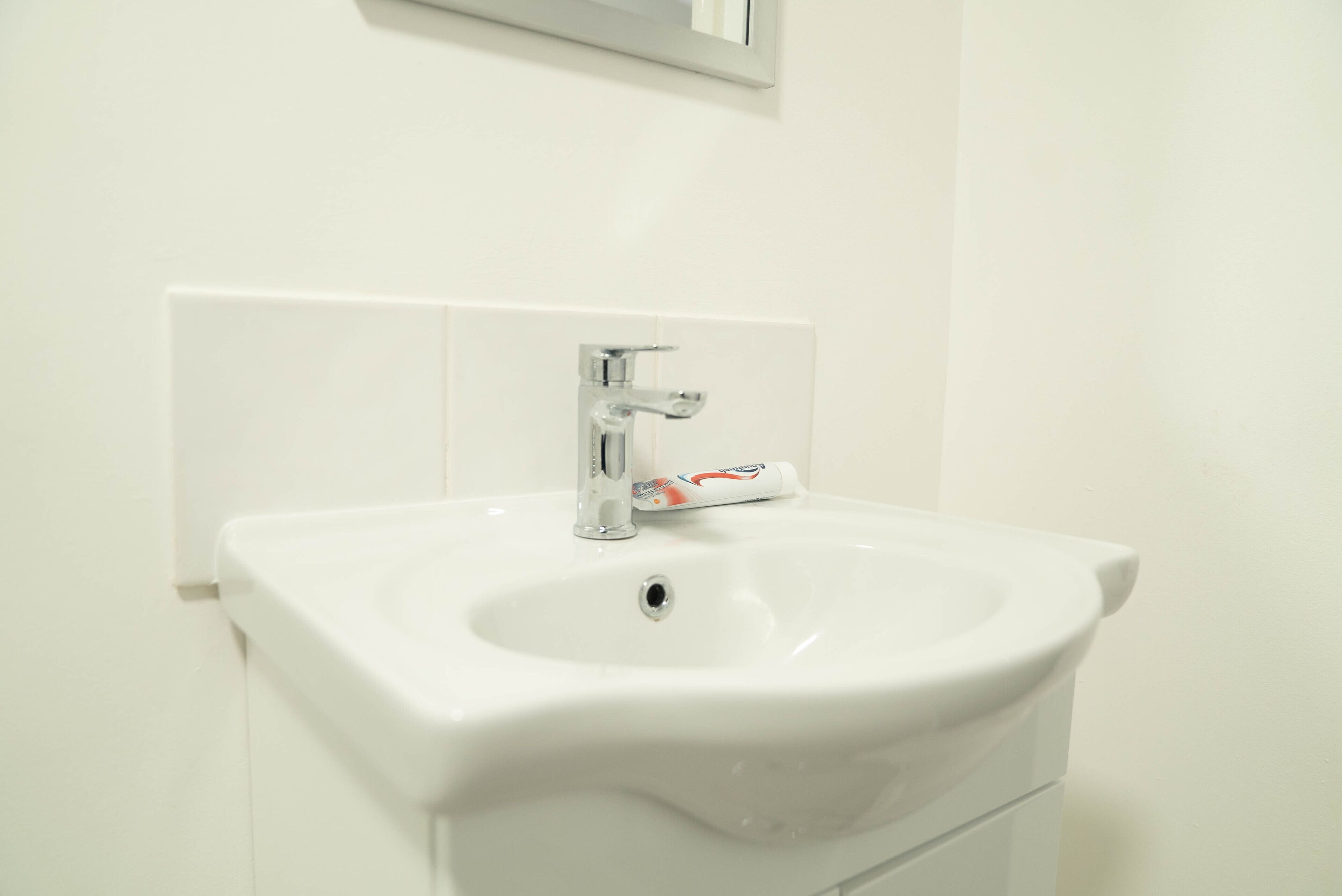 A white bathroom sink with a chrome faucet and a soap dispenser.