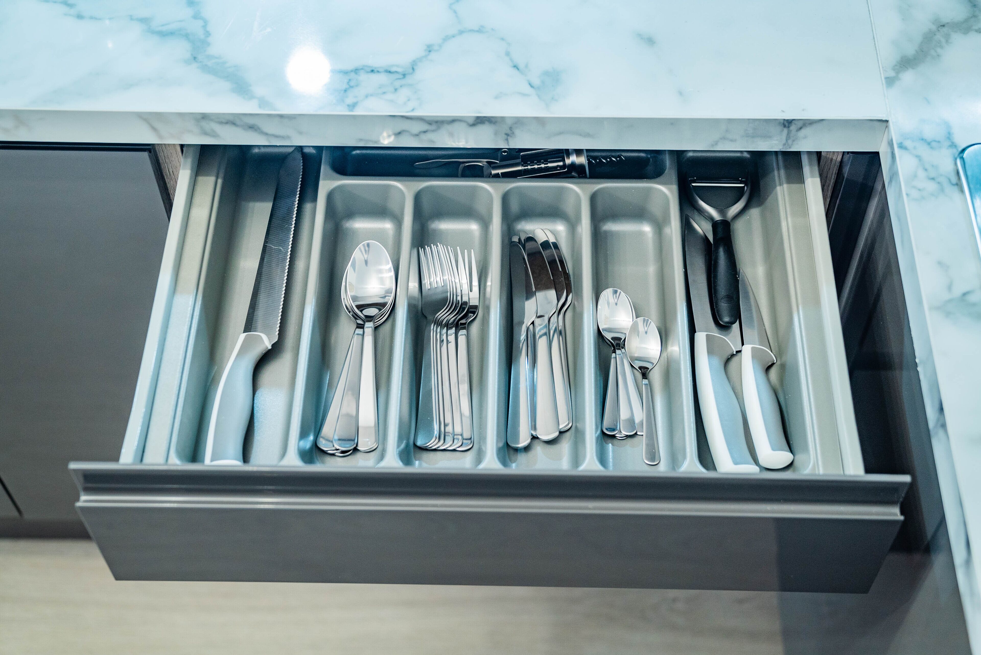 A drawer with neatly organized silverware including forks, spoons, and knives.