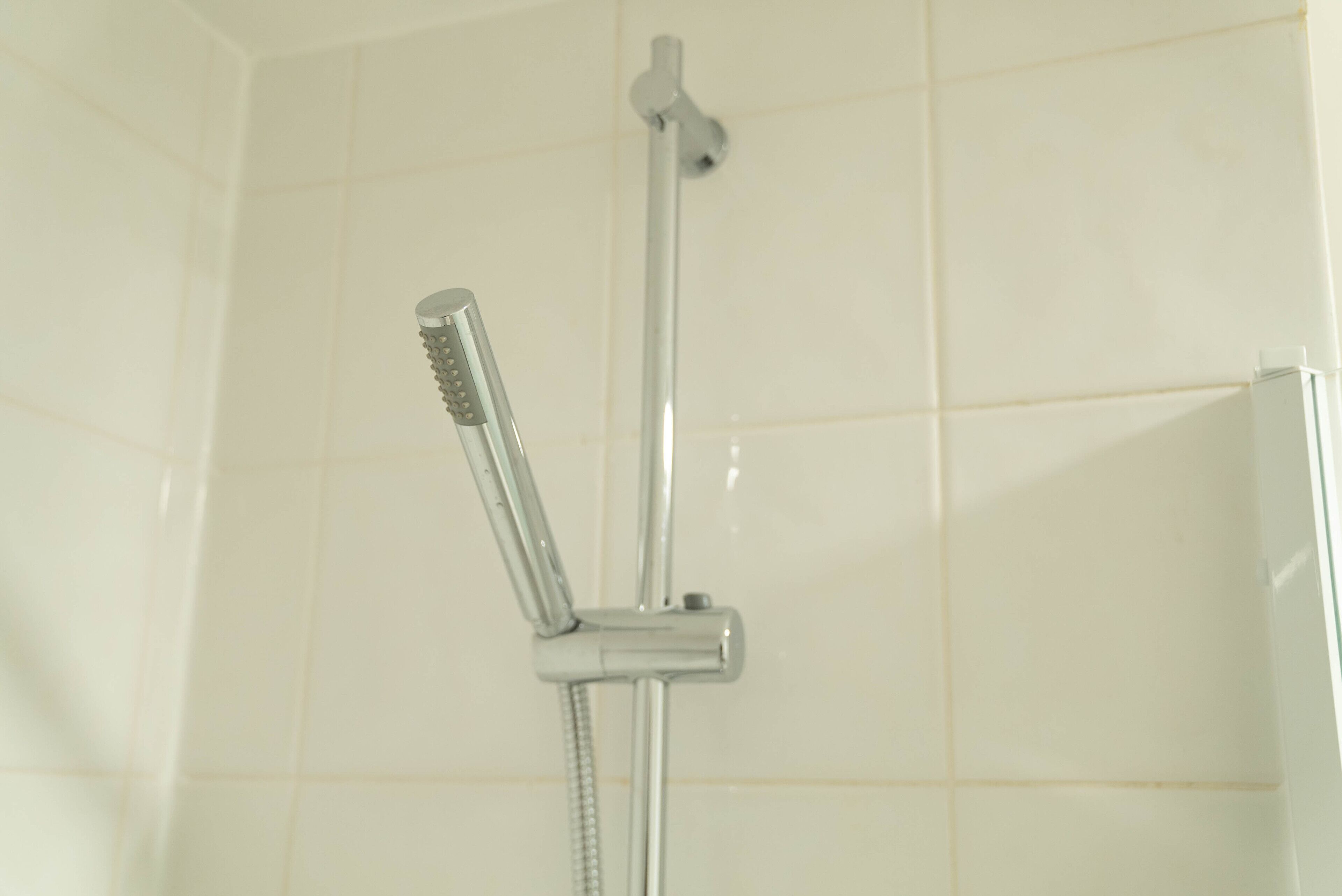 A shower with a handheld showerhead and a fixed overhead showerhead in a tiled bathroom.