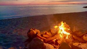 A beach scene with a fire on the sand and a clear sky. - BAY HOUSE - Steps to its own Private Beach - Amazing Sunsets on the Water (Pensacola)