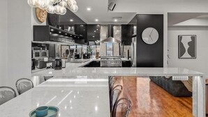 A modern kitchen with a central island, stainless steel appliances, and a hanging light fixture. - StayCentral - Moonee Ponds Penthouse - Mount Alexander Rd, Moonee Ponds - 3 Bedrooms, 4 Beds, 2 Bathrooms, 2 secure undercover parking spot. (Moonee Ponds)