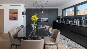 Et moderne køkken med mørke skabe, et spisebord i sort marmor og en vase med gule blomster.