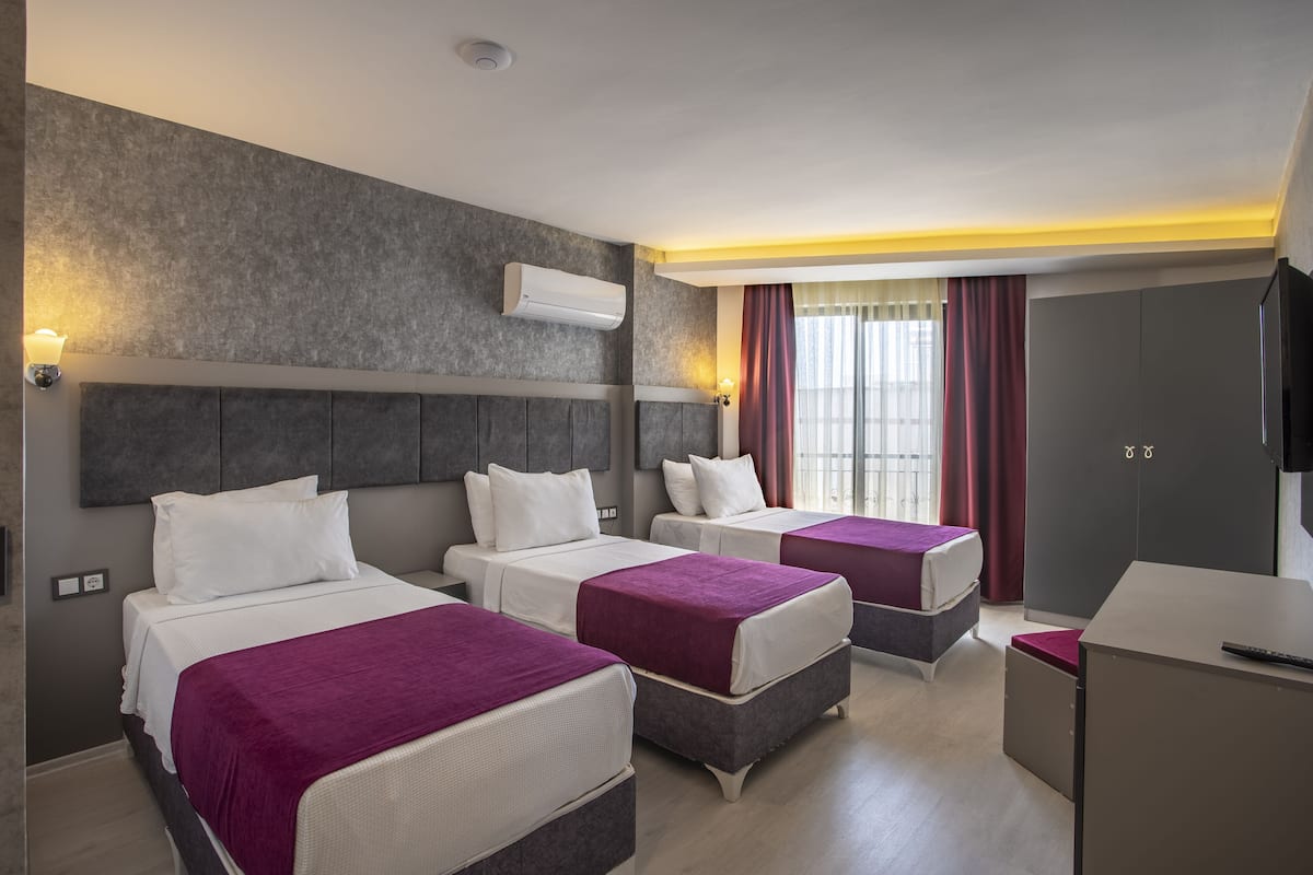 Een hotelkamer met drie bedden, een bureau en een televisie.