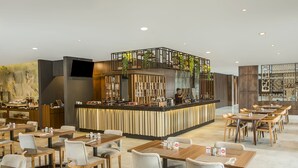 Ein modernes Restaurant mit einer zentralen Bar, verschiedenen Sitzgelegenheiten und einer Wanddekoration mit Pflanzen.