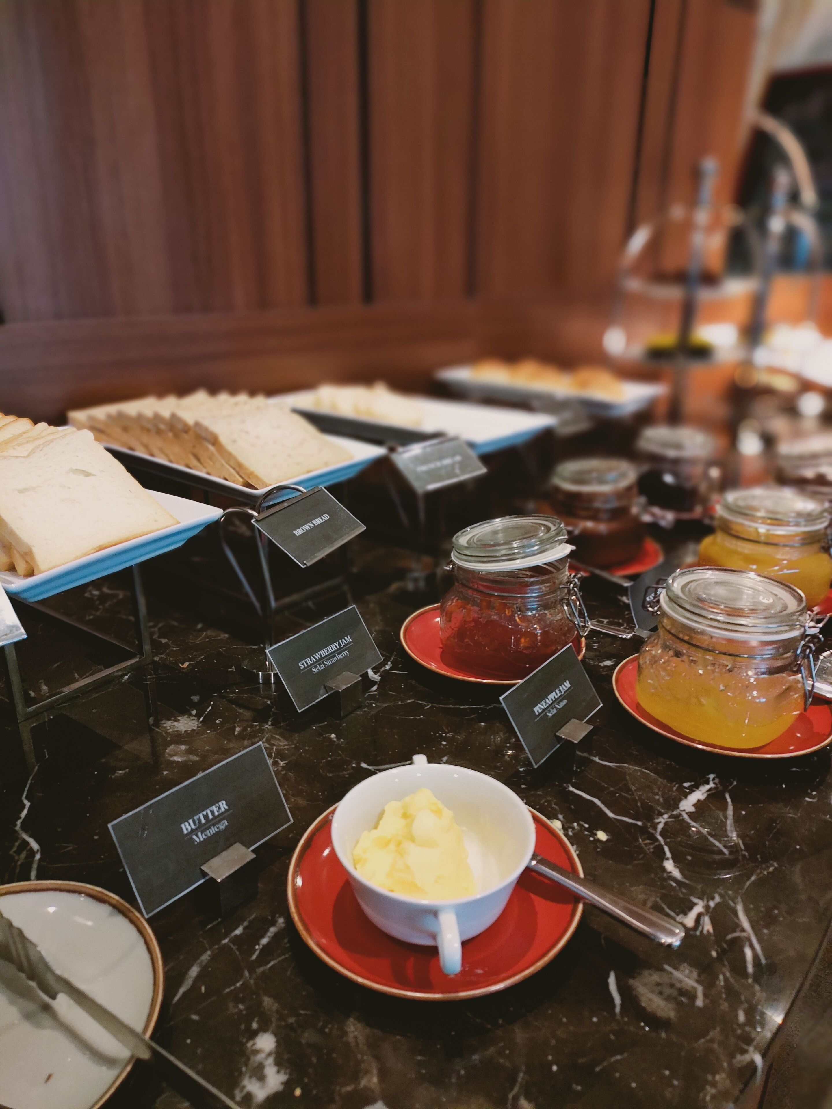 A buffet with labeled food items including butter, jam, and bread.