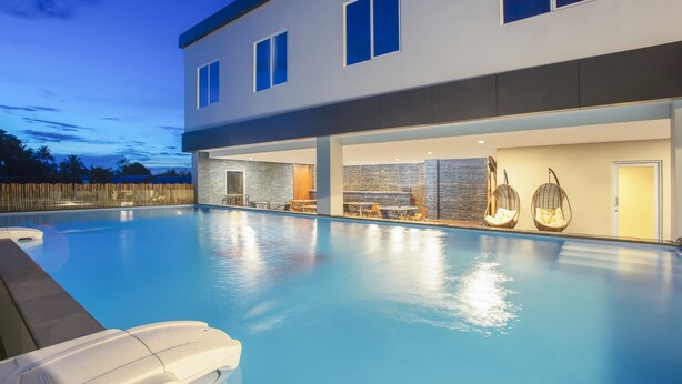 Ein modernes Haus mit Swimmingpool, Sitzgelegenheiten im Freien und einer gut beleuchteten Terrasse.
